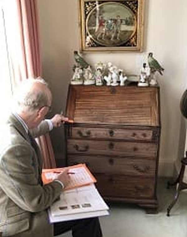 A Kidson-Trigg valuer inspecting a bureau